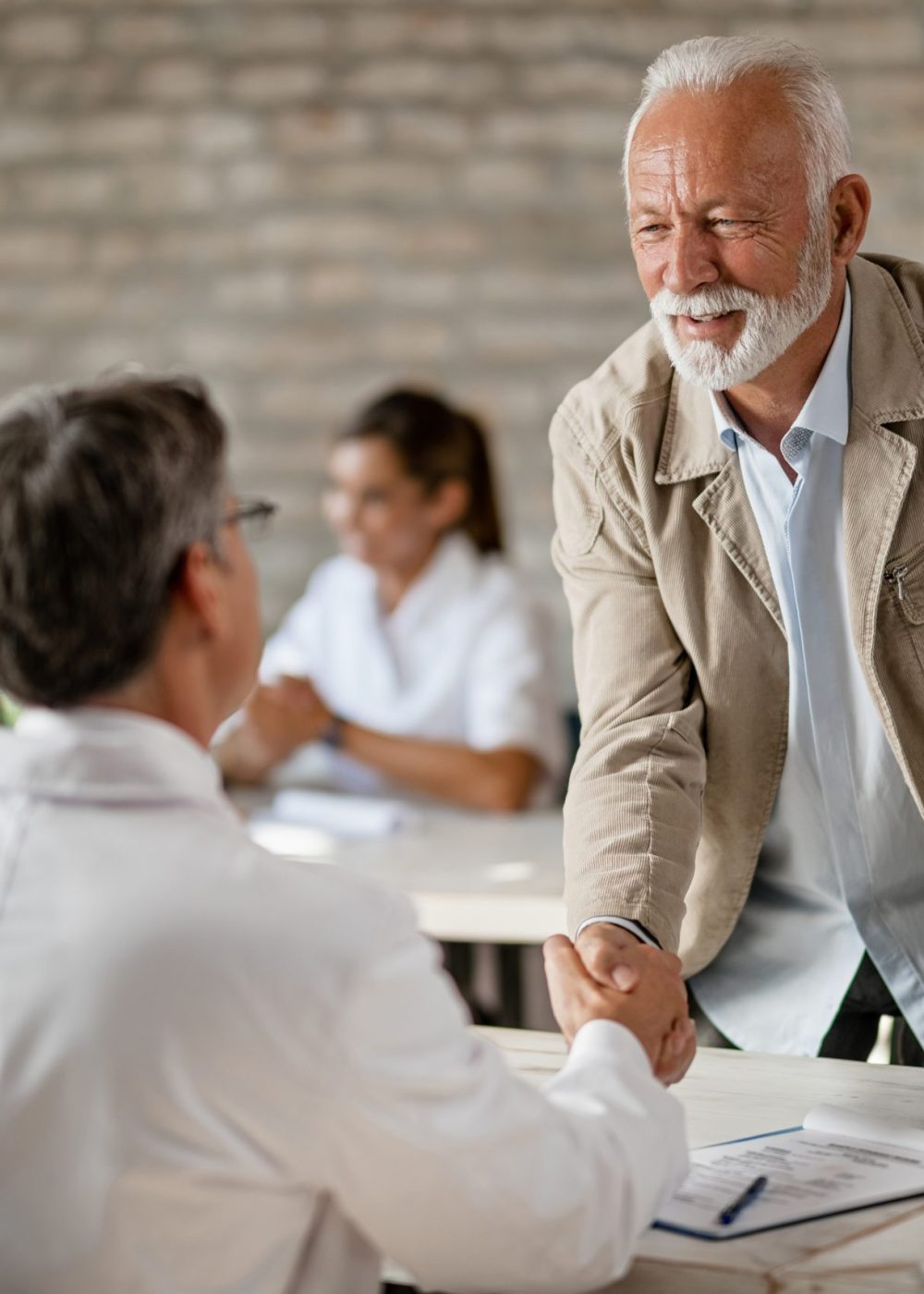 Happy senior man shaking hands with a doctor after consultations at clinic.
