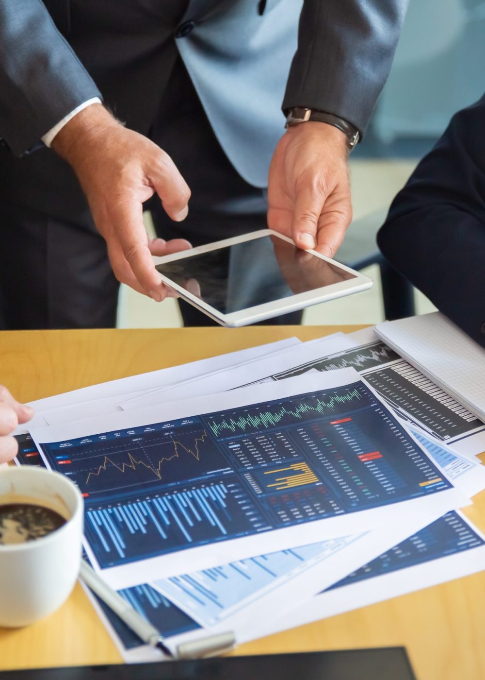 Unrecognizable business partners working with statistic charts. Businessman holding tablet. Professional content businesswoman making notes for statistics. Communication and partnership concept